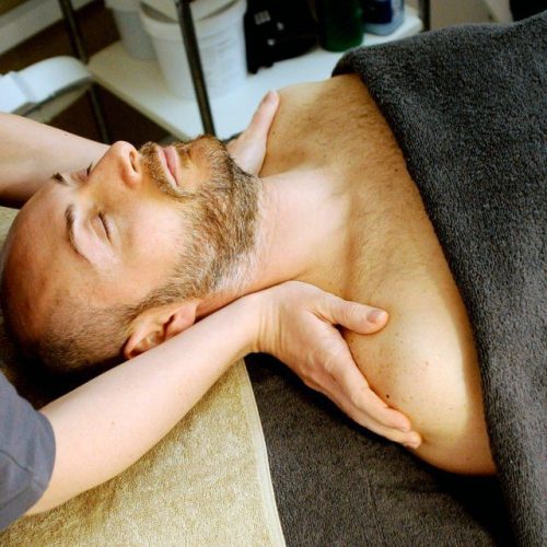 Gentleman On Massage Table Having Shoulders Massaged